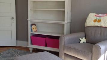 Cozy retreat with a plush armchair and matching ottoman, complemented by a stylish bookshelf and patterned rug.