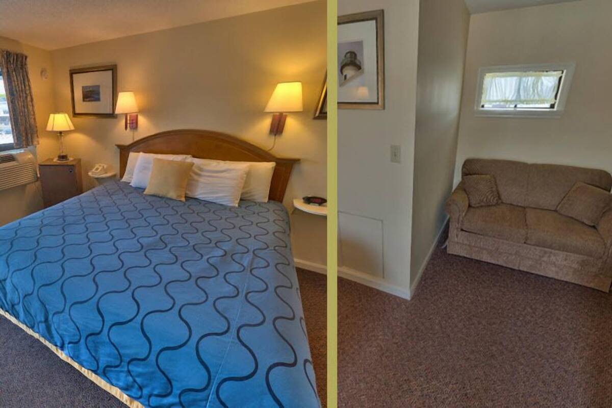 A hotel room with a bed, two bedside lamps, a nightstand with a phone, a window with curtains, and a brown sofa.