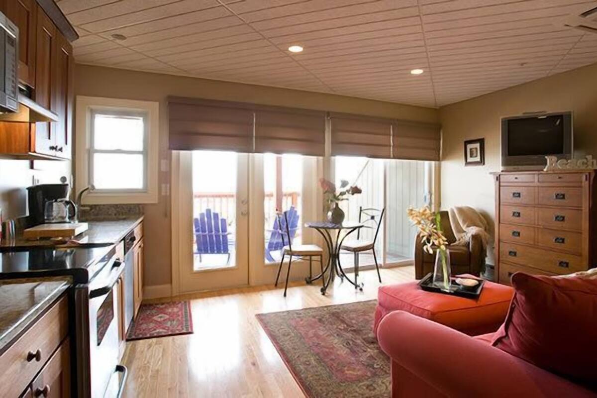 A spacious living area with a kitchen, a red sofa, a television, and a large window.