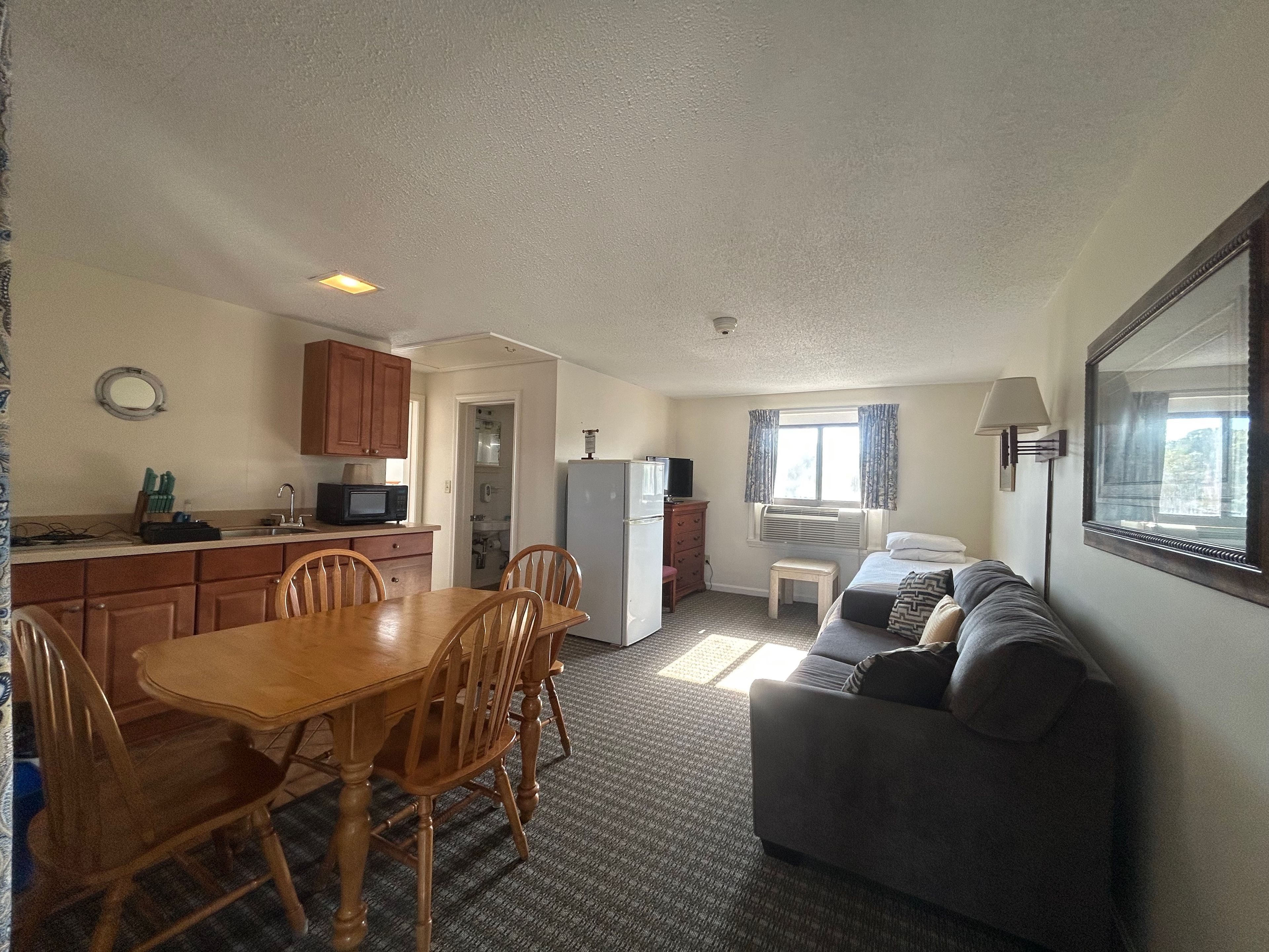 A compact living space with a dining area, kitchenette, and a sofa.
