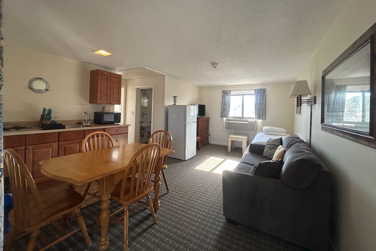 A compact living space with a dining area, kitchenette, and a sofa.