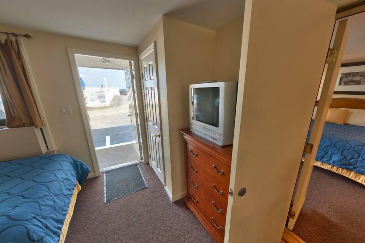 A room with a bed, a dresser, a television, and a door leading outside.