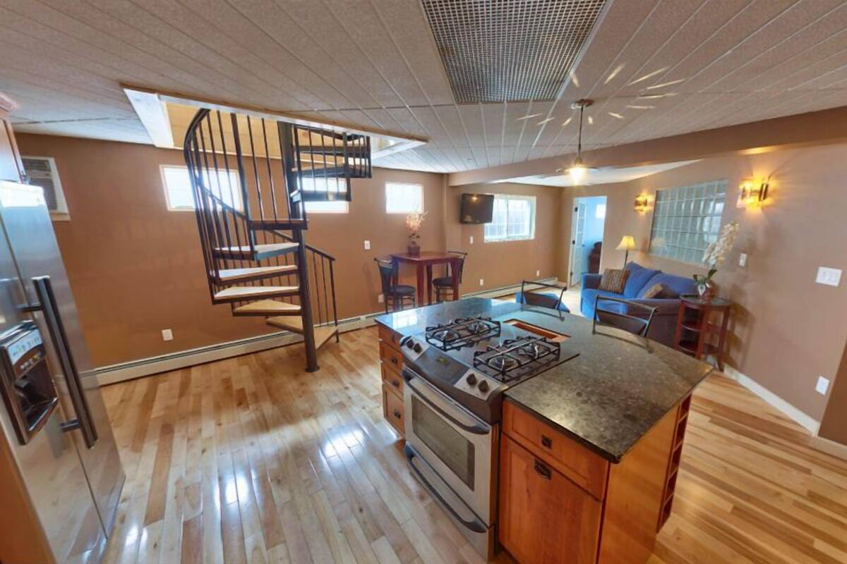 A kitchen with a central island, a built-in stove, and a spiral staircase.