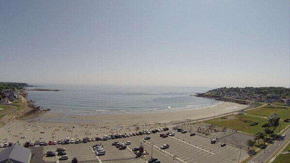 A coastal area with a beach, parking lot, and buildings. - Sands by the Sea Motel (York Beach)
