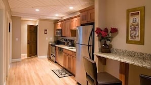 A kitchen with wooden cabinets, a stainless steel refrigerator, and a granite countertop. - Sands by the Sea Motel (York Beach)