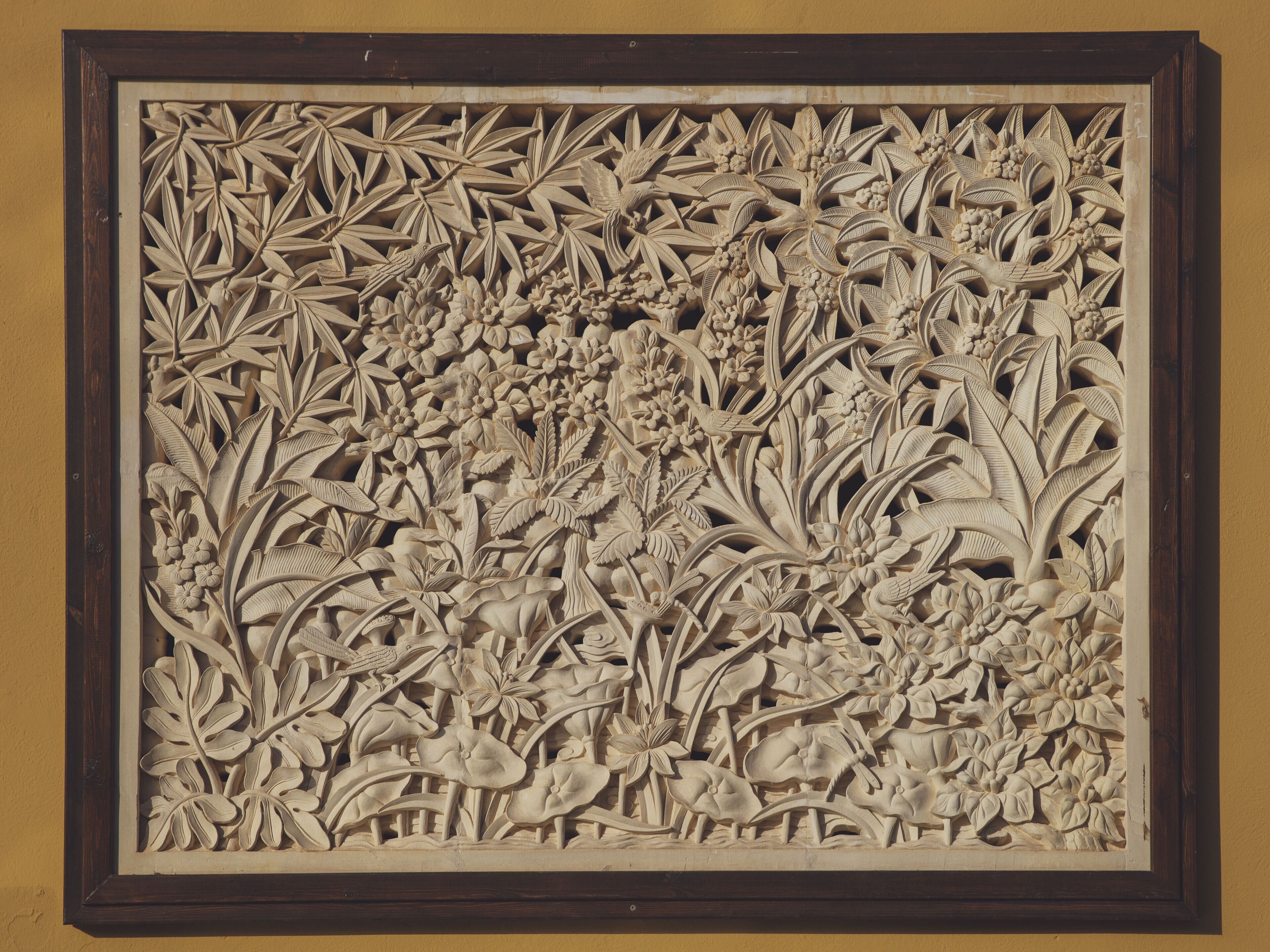 Un pannello intarsiato con decorazioni floreali e motivi di uccelli.
