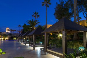A covered outdoor seating area with lounge chairs and a pool in the background. - Apartamentos Atlantic Garden Beach Mate (La Oliva)