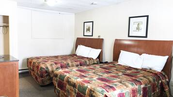 A hotel room with two single beds, a wooden headboard, a desk, and a trash bin.