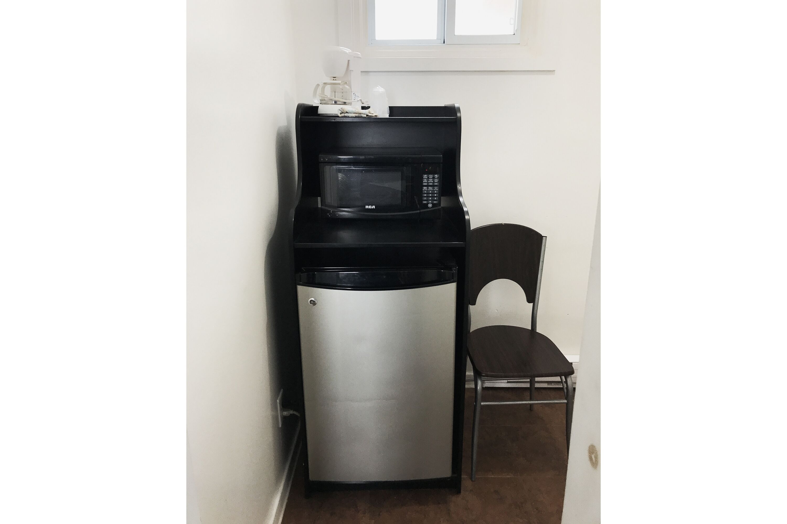A compact kitchenette with a microwave and a small refrigerator.
