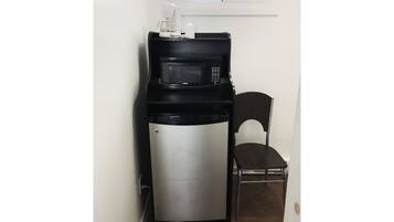 A compact kitchenette with a microwave and a small refrigerator.
