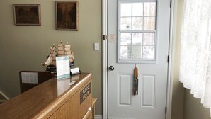A reception desk with a 'Please Sign In' sign, framed pictures on the wall, and a white door with a window. - Bayside Motel (Quinte West)