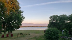 A view of a lake with a grassy area and a few chairs. - Bayside Motel (Quinte West)