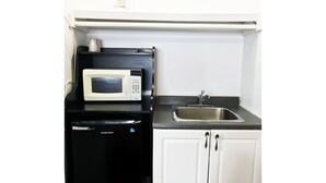 A compact kitchen with a microwave, dishwasher, and a sink. - Bayside Motel (Quinte West)