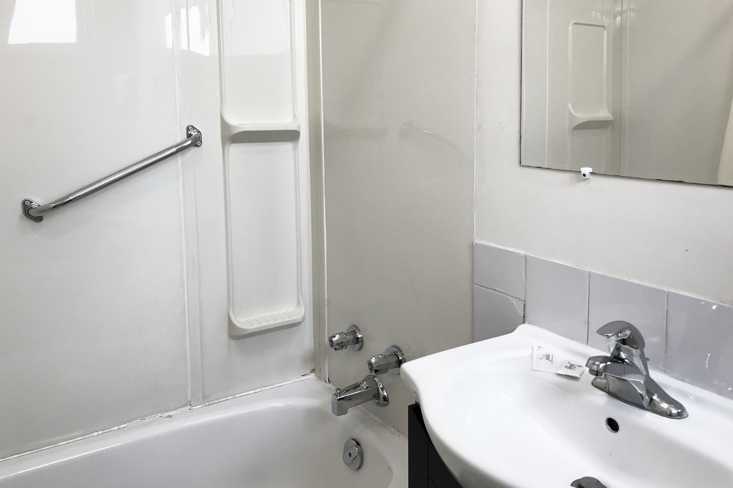 A bathroom with a white sink, a mirror, and a shower area.