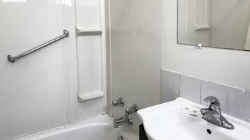 A bathroom with a white sink, a mirror, and a shower area.