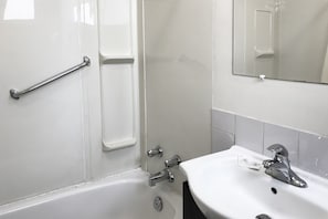 A bathroom with a white sink, a mirror, and a shower area. - Bayside Motel (Quinte West)