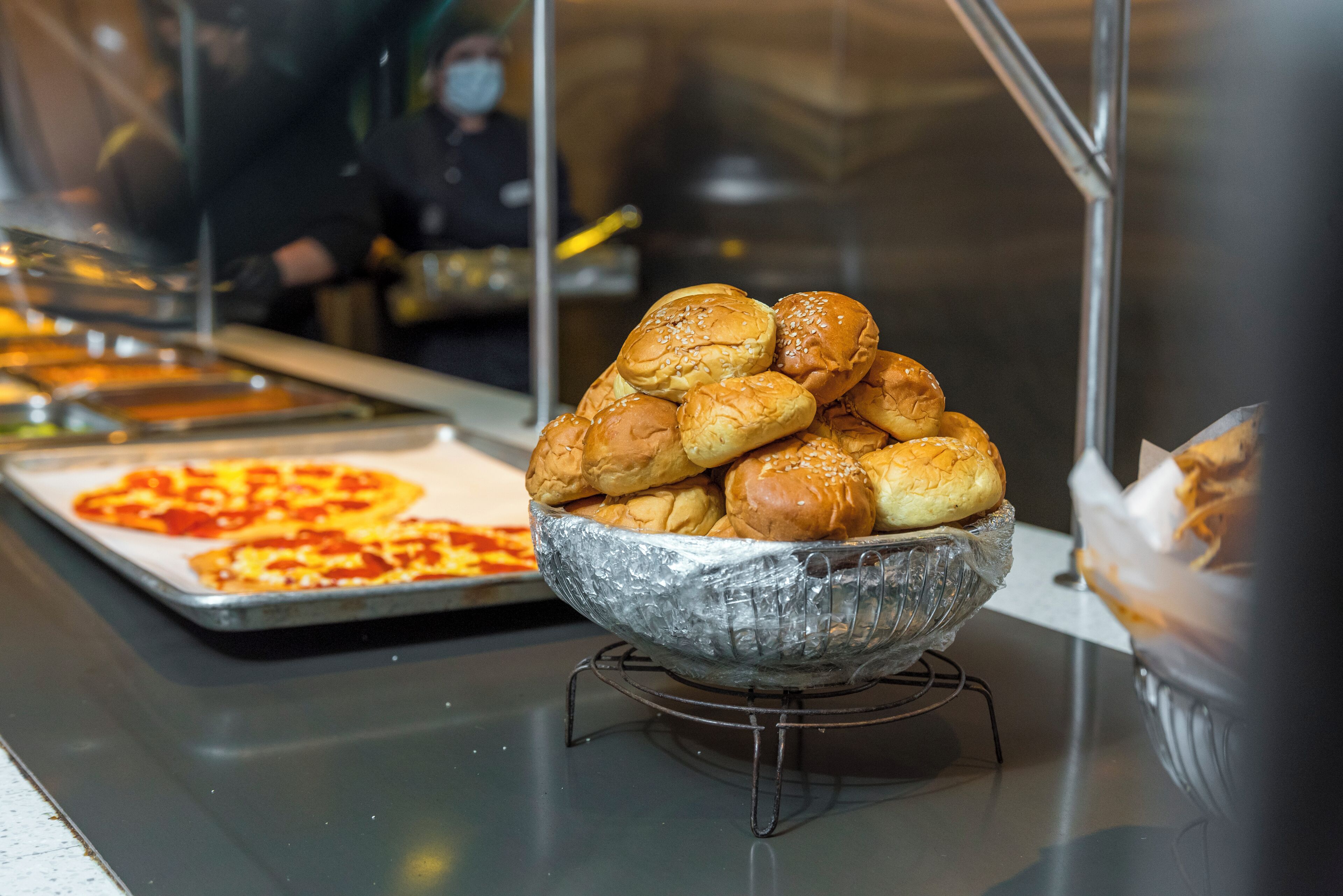 Un buffet proposant une variété de plats, notamment un panier de petits pains et une assiette de pizzas.