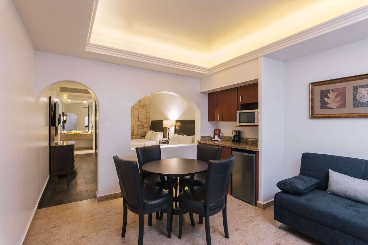 A compact living space with a dining area, kitchenette, and a sofa.