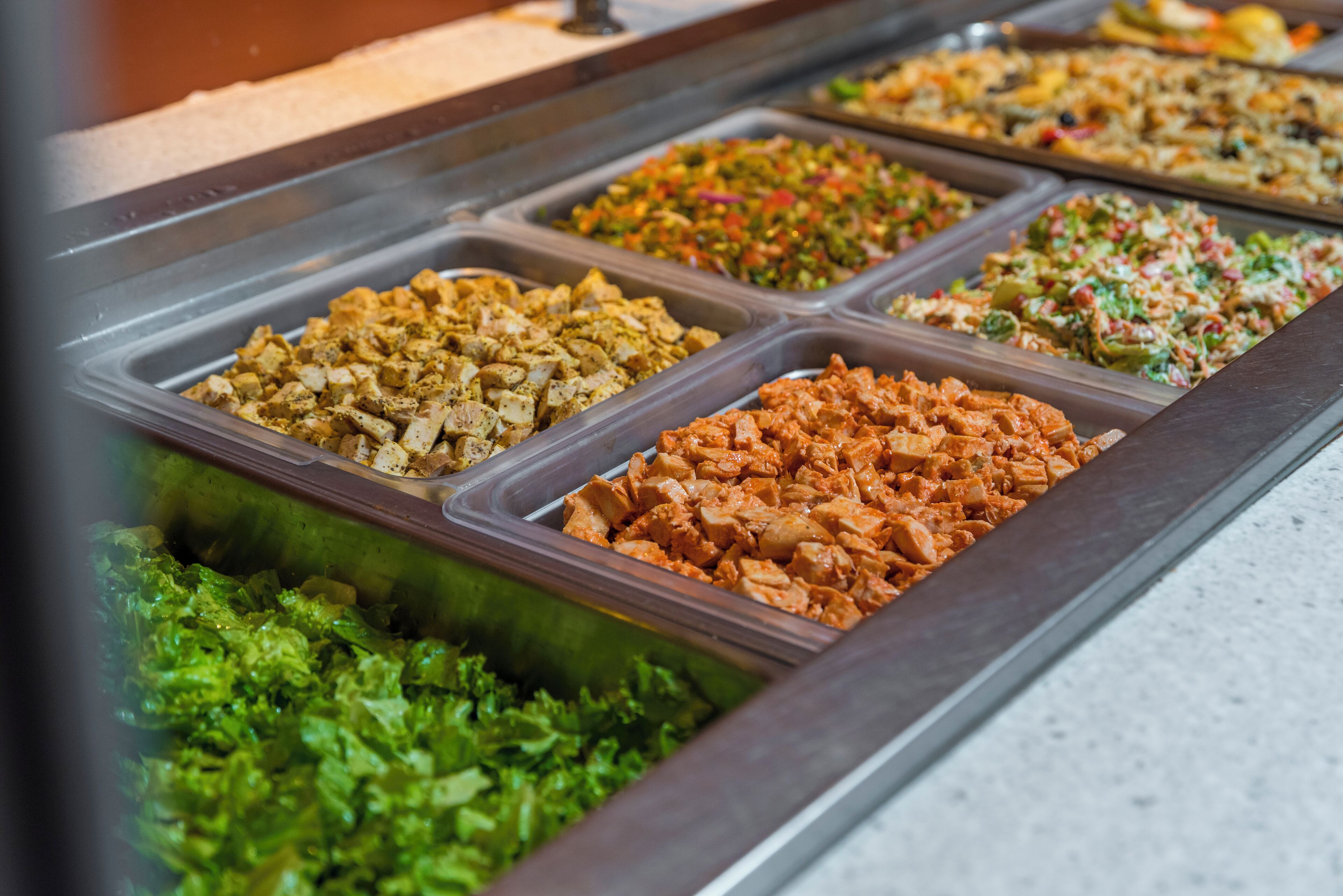 A buffet with various food options including salads, meats, and other dishes.