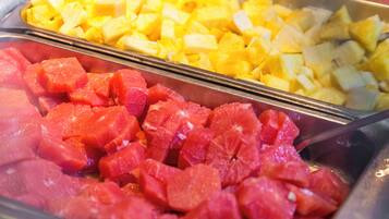 A buffet with various fruits including pineapple, watermelon, and mango.