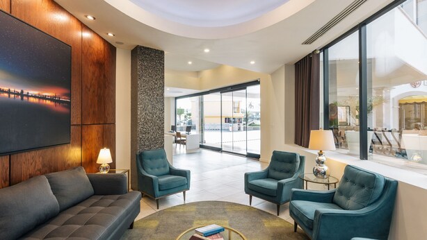 Un hall d’entrée moderne avec un canapé, des fauteuils, une table basse et un grand écran de télévision.