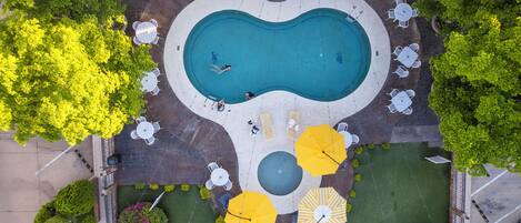 An aerial view of a swimming pool area with surrounding seating and greenery.
