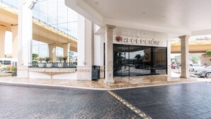 L’entrée d’un hôtel, avec un espace d’accueil, de grandes fenêtres en verre et un sol carrelé.