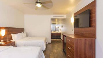 A hotel room with two beds, a wooden dresser, a ceiling fan, and a large mirror.