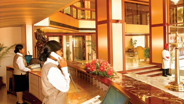 A hotel lobby with a reception desk, a statue, and a chandelier. - Classic Sarovar Portico Thiruvananthapuram (Thiruvananthapuram)