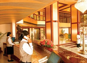 A hotel lobby with a reception desk, a statue, and a chandelier. - Classic Sarovar Portico Thiruvananthapuram (Thiruvananthapuram)