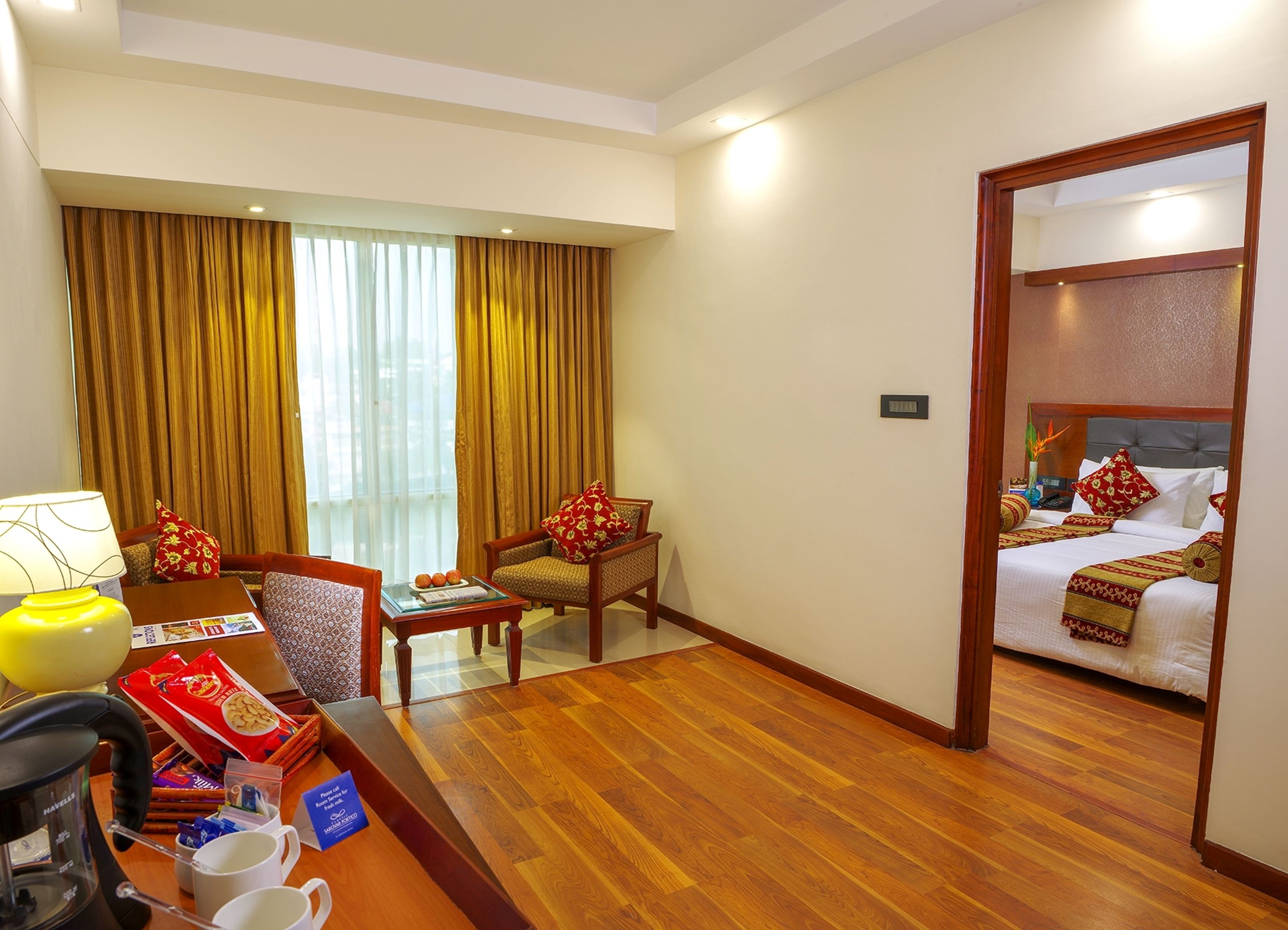 A hotel room with a bed, a desk with a coffee maker, a chair, and a sofa.
