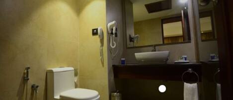 A bathroom with a toilet, a sink, a mirror, and a shower.