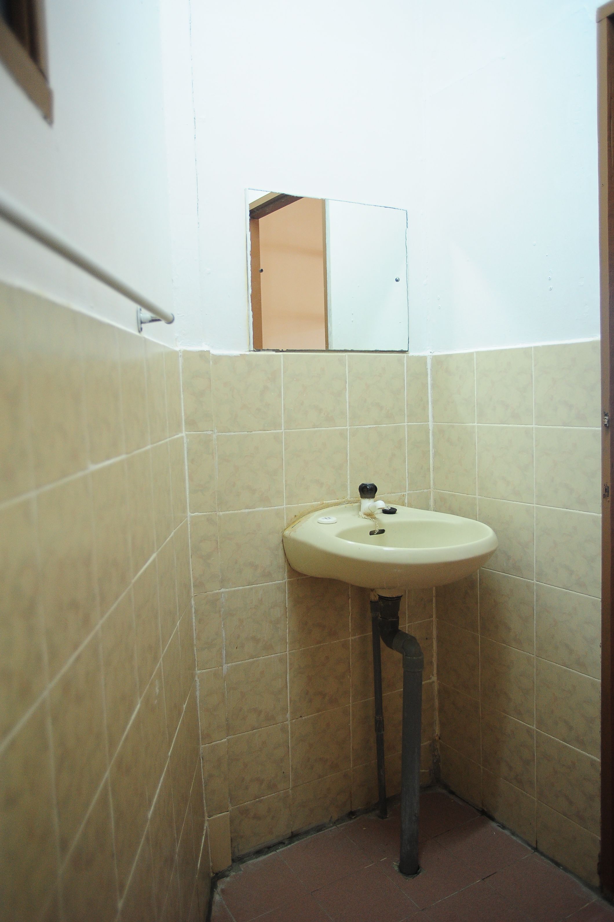 A small bathroom with a sink, mirror, and tiled walls.