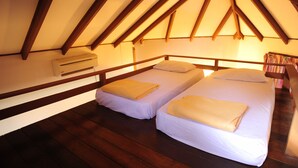 Una camera da letto mansardata piccola e accogliente con due letti singoli, travi in legno e condizionatore d'aria integrato.