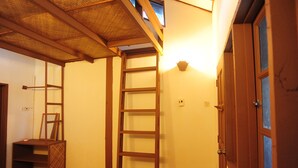 Una stanza con una scala in legno, un piccolo ripiano e una porta con finestre.