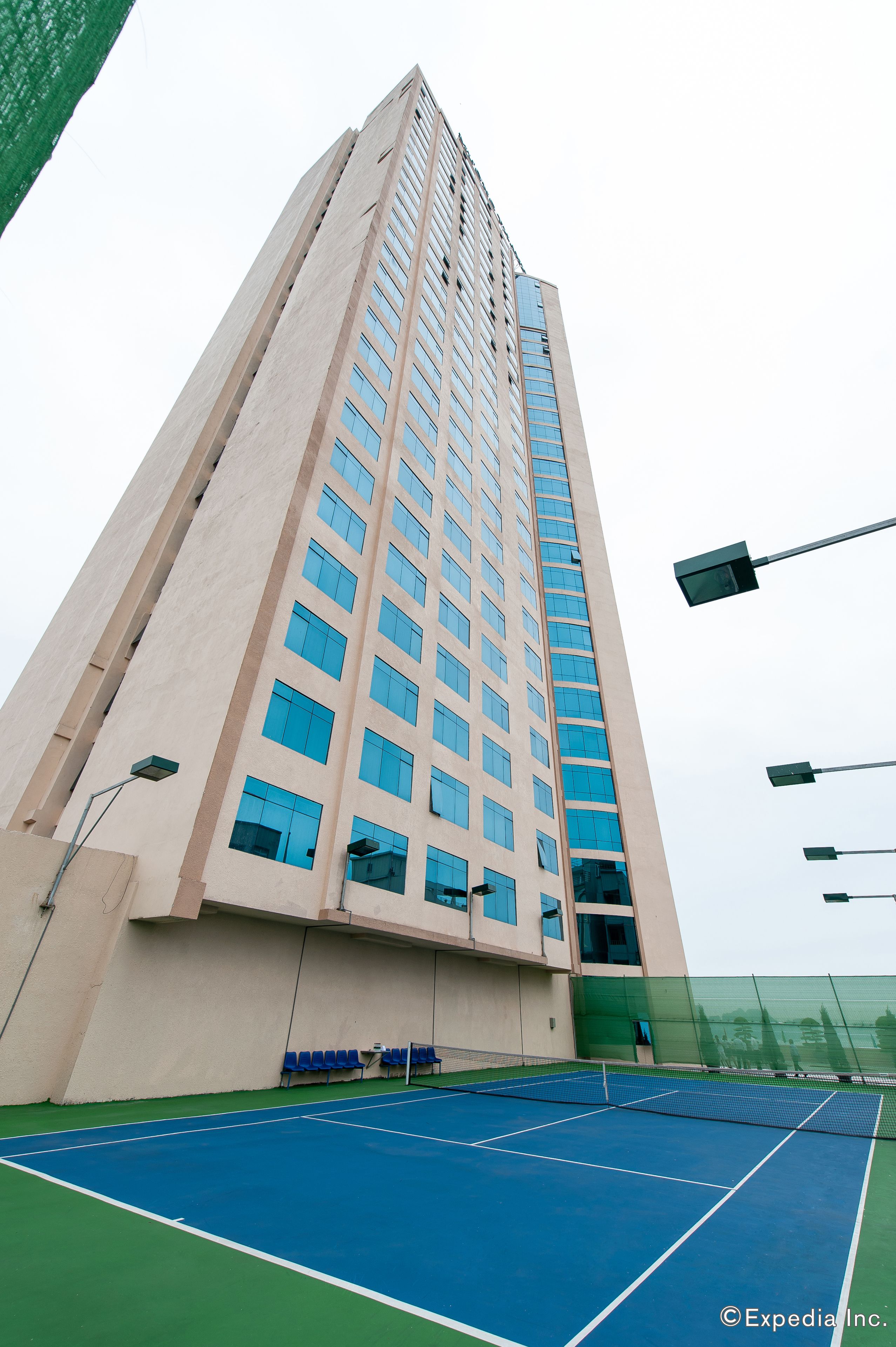 A tall building with a tennis court in front.