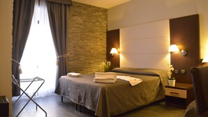 A hotel room with two beds, a wall-mounted TV, a bedside table with a lamp, and a window with curtains. - B&B La Casa di Patty (Rome)
