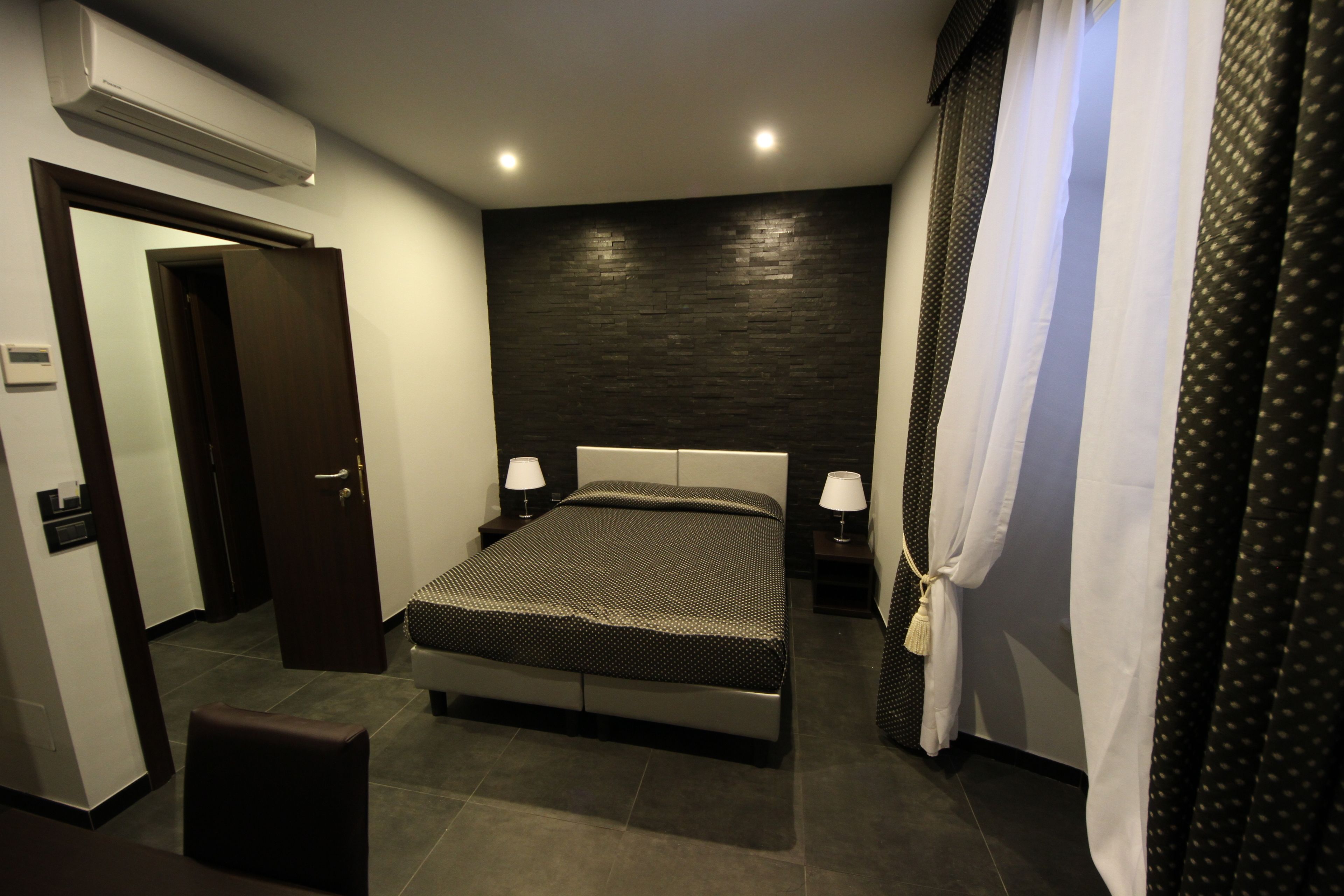 A modern bedroom with a bed, bedside tables, a chair, and a door.