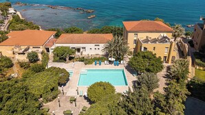 A coastal hotel with a swimming pool, multiple buildings, and a view of the sea. - Villa Andromeda (Chania)