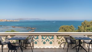 A balcony with a table and chairs overlooking a coastal view. - Villa Andromeda (Chania)