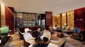 A spacious lobby with a bar area, seating arrangements, and a patterned carpet.