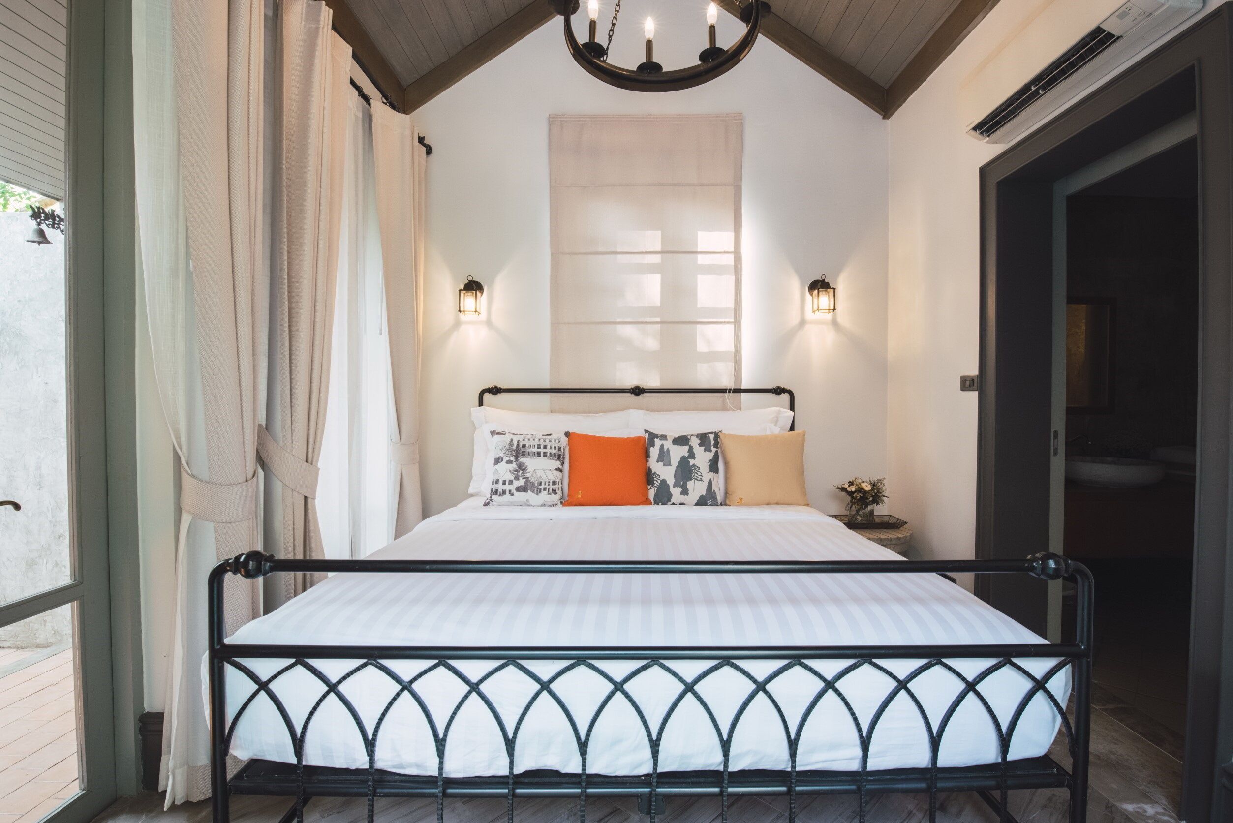 Ein Schlafzimmer mit einem Bett, Vorhängen, Wandleuchten und einer Deckenleuchte.