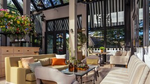 Un intérieur moderne avec un canapé, des fauteuils, une table basse et une composition florale suspendue.