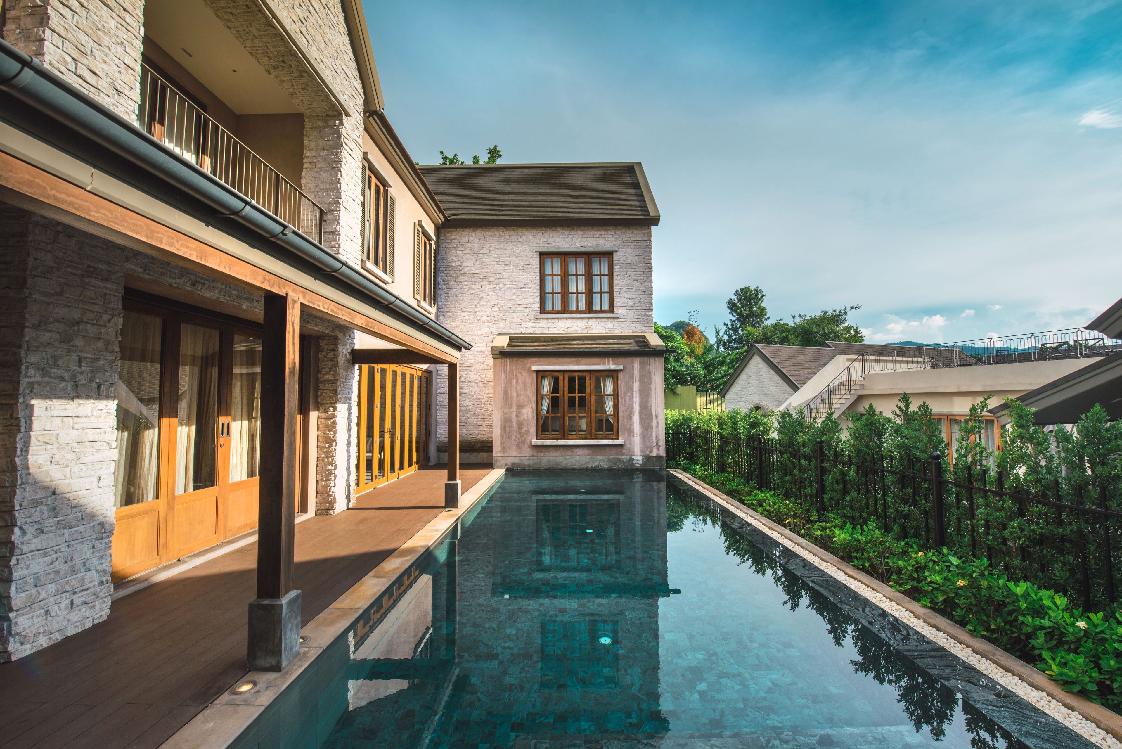 A modern house with a swimming pool, stone facade, and a balcony.