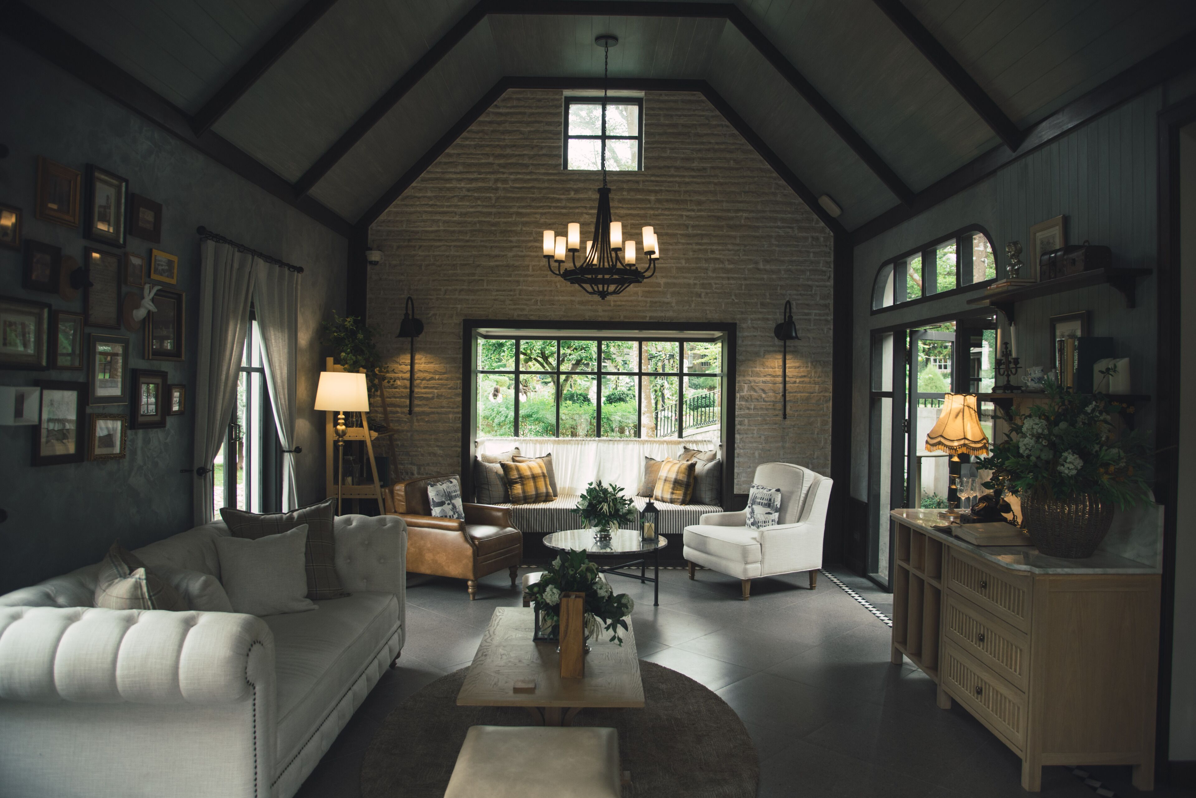 A spacious living room with a high ceiling, a large window, and a chandelier.