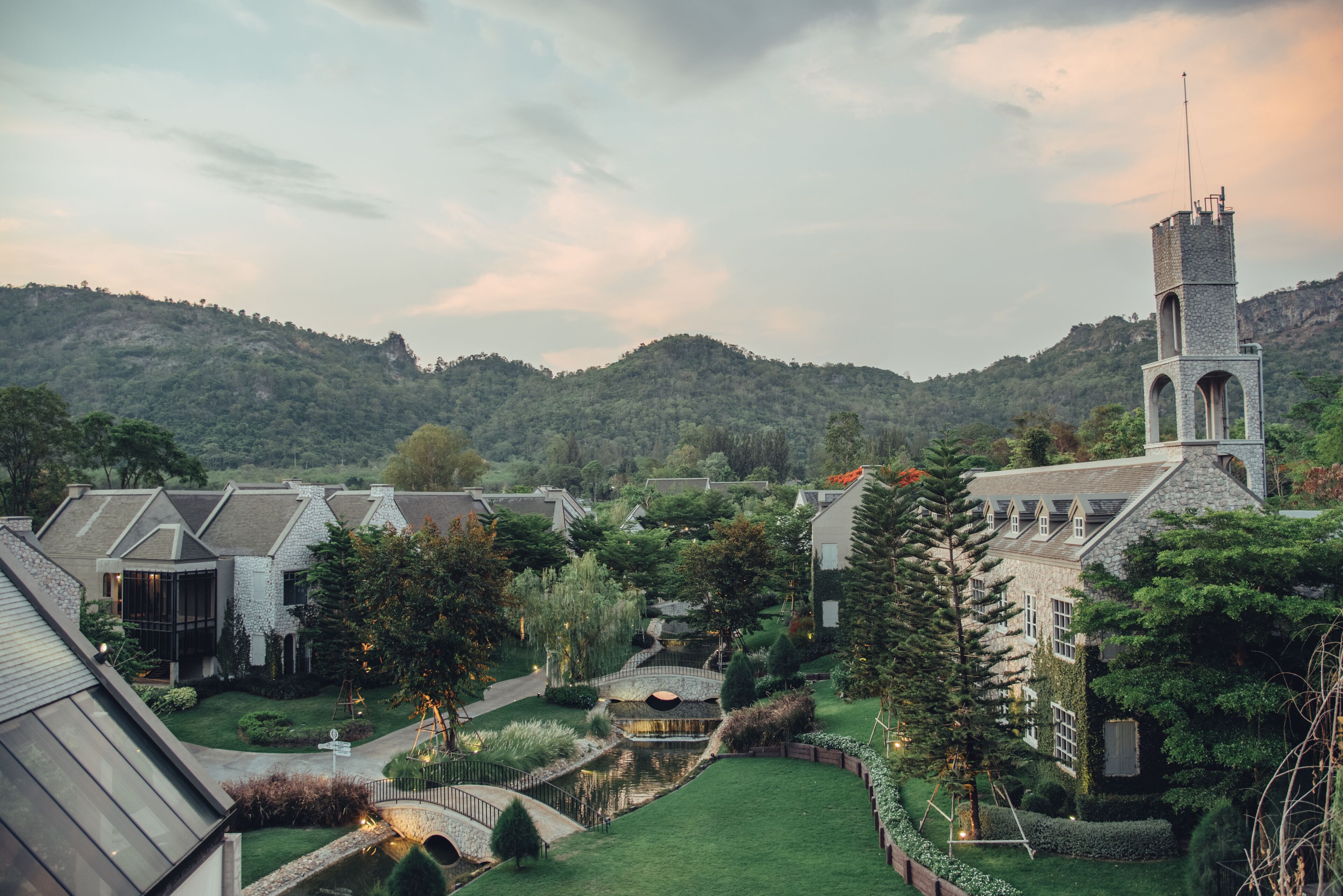 A residential area with a prominent tower, lush greenery, and a small water feature.