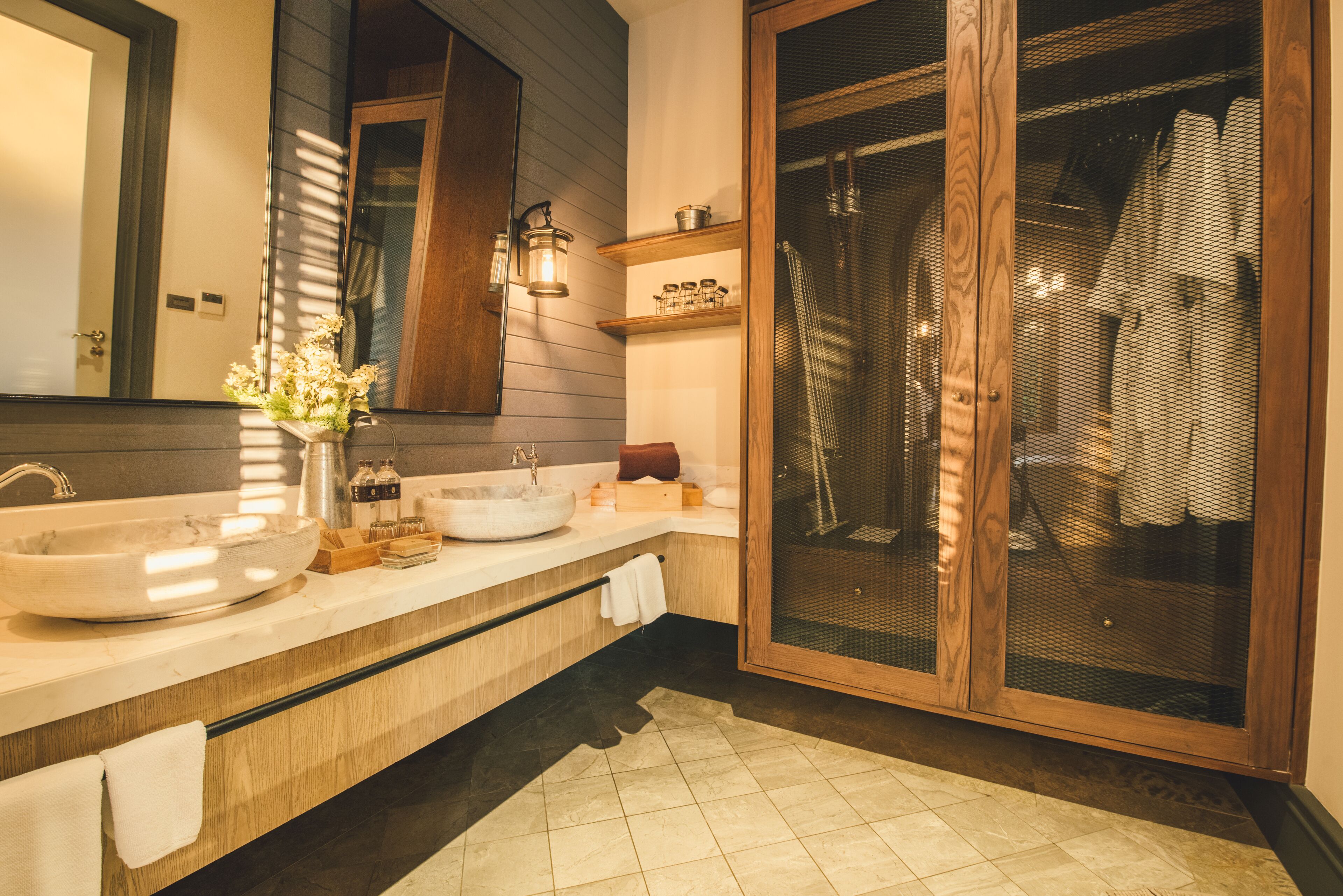 A modern bathroom with a large sink, wooden cabinets, and a glass shower enclosure.