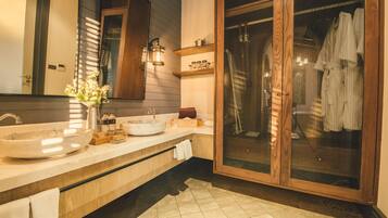 A modern bathroom with a large sink, wooden cabinets, and a glass shower enclosure.