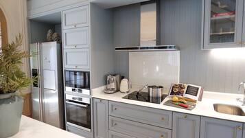 A modern kitchen with grey cabinetry, stainless steel appliances, and a white countertop.