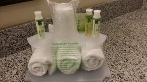 A hotel bathroom with toiletries including lotion, shampoo, and conditioner. A sign states the hotel's hospitality promise and offers complimentary replacements for forgotten items. - Holiday Inn Express & Suites York by IHG (York)